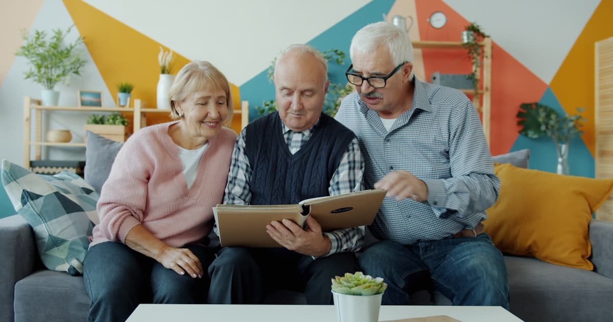 Three seniors looking at a photo album together.